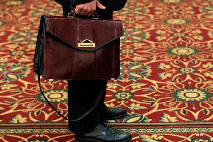 A man holds his briefcase while waiting in line during a job fair in Melville, New York, July 19, 2012. Reuters