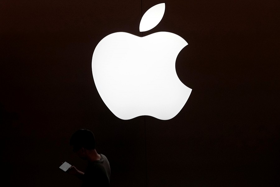 A man looks at the screen of his mobile phone in front of an Apple logo — Reuters/File