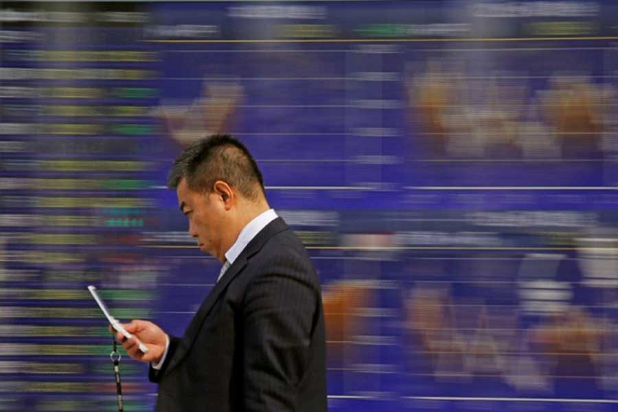 A man walks past an electronic stock quotation board outside a brokerage in Tokyo, Japan, February 9, 2018. Reuters/Files