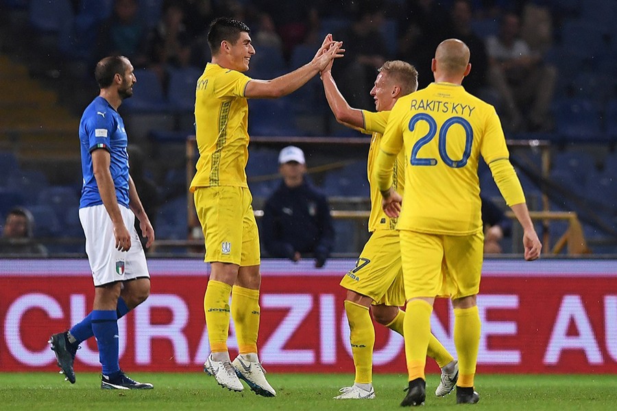 Italy's Giorgio Chiellini looks dejected as Ukraine's Ruslan Malinovsky celebrates scoring their first goal with teammates — Reuters action image