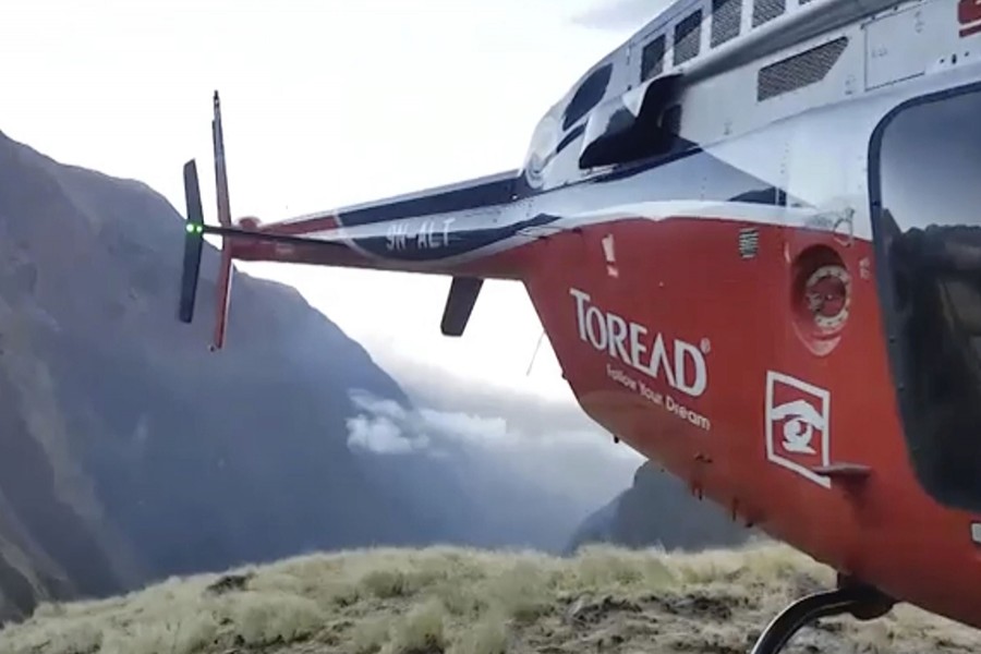 In this grab taken from video provided by SIMRIK AIR, a helicopter lands close to a storm site after searching for missing mountaineers on the Gurja Himal mountain, in Nepal on Saturday — via AP