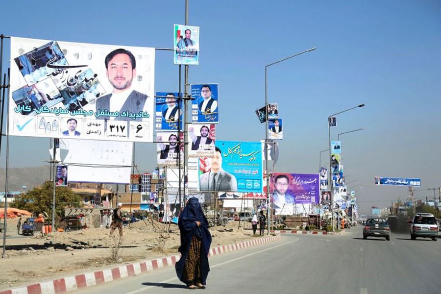 Campaign posters for parliamentary candidate are displayed over a street for the upcoming election, as a woman waits for transportation in Kabul, Afghanistan, Tuesday, Oct 9, 2018 - AP