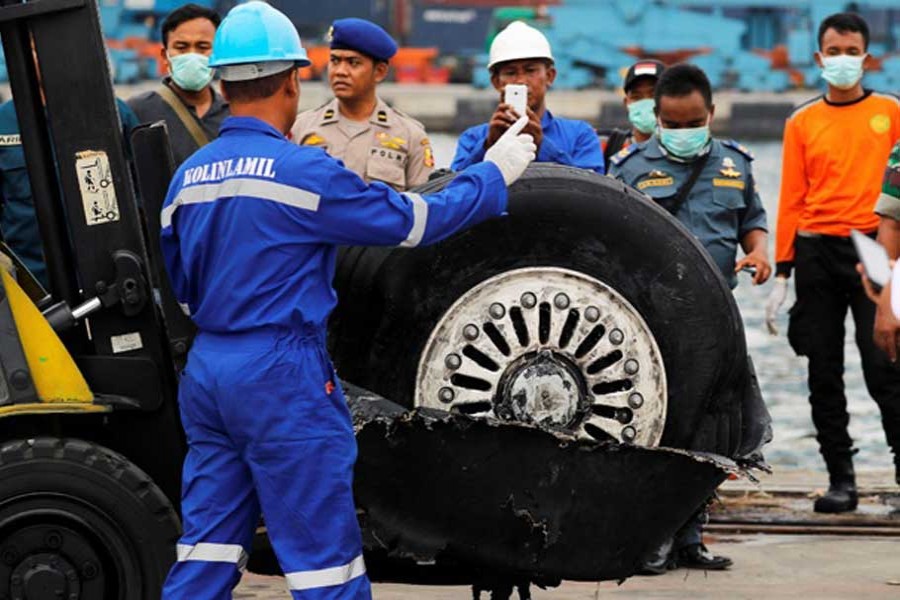 A worker assists his colleague during the lift up of a damaged tyre from the Lion Air flight JT610 jet, at Tanjung Priok port in Jakarta, Indonesia, Nov 5, 2018. - Reuters