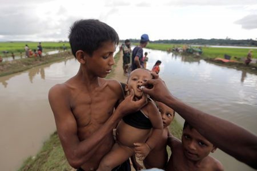 A Rohingya refugee boy who crossed the border from Myanmar a day before, gets an oral cholera vaccine, distributed by UNICEF workers as he waits to receive permission from the Bangladeshi army to continue his way to the refugee camps, in Palang Khali, near Cox's Bazar, Bangladesh October 17, 2017. Reuters/File photo