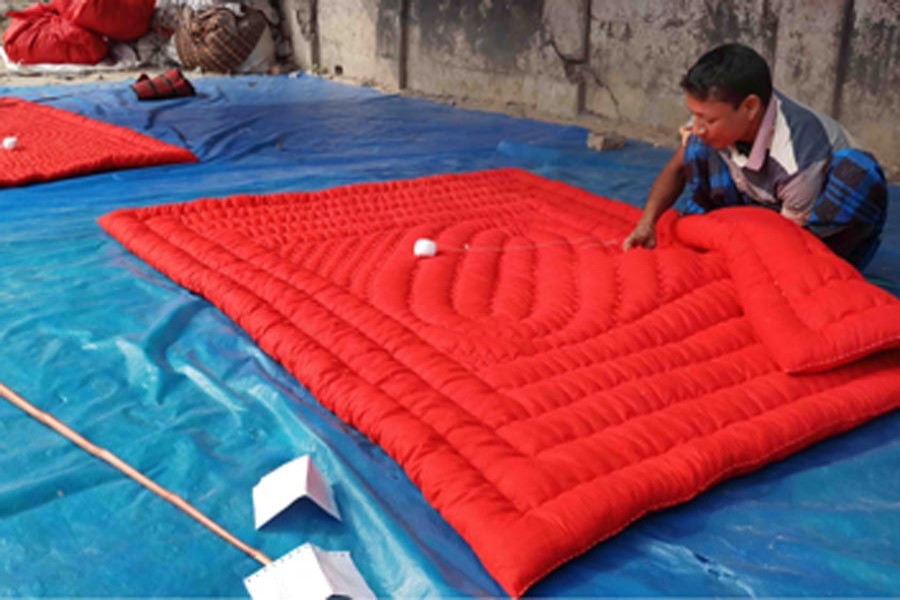 A quilt maker working at his shop in Mohadevpur upazila of Naogaon on Tuesday   	— FE Photo