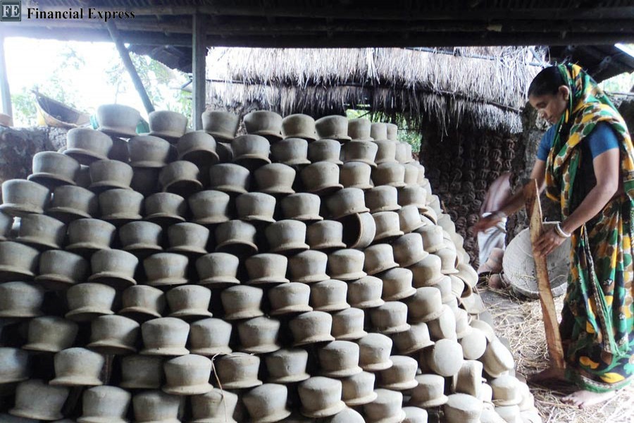 A female potter taking preparation to burn the earthen pots at Kalai Paul Para under Kahaloo Upazila of Bogura district