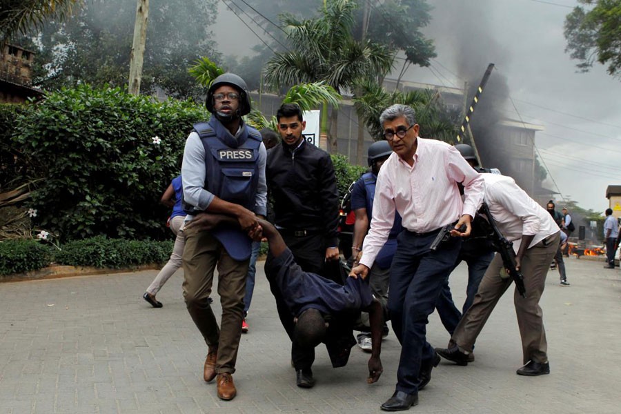 Rescuers and journalists evacuate an injured man from the scene where explosions and gunshots were heard at the Dusit hotel compound, in Nairobi, Kenya January 15, 2019 - REUTERS/Njeri Mwangi