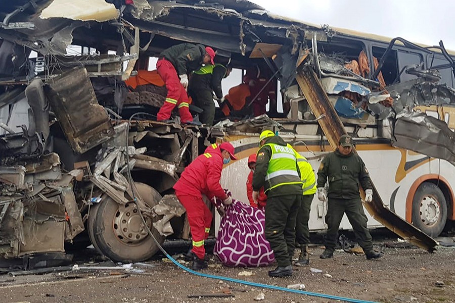 In this photo released by the Bolivian Police of Oruro, firefighters and police help a victim of a crash of two buses on the outskirts of Challapata, Bolivia on Saturday — via AP