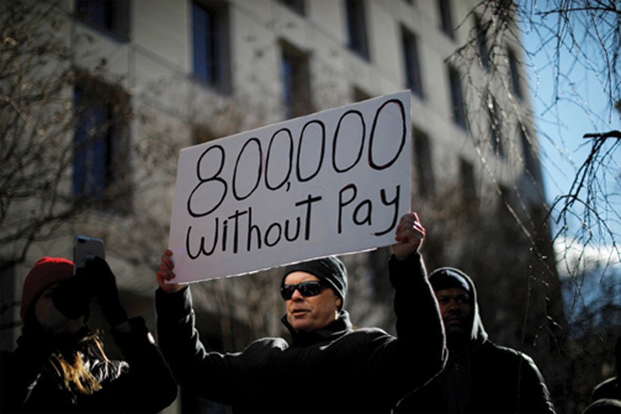 A demonstrator holding a sign, signifying hundreds of thousands of federal employees who won't be receiving their paychecks as a result of the partial government shutdown, during a rally in Washington on January 10, 2019. — Reuters         