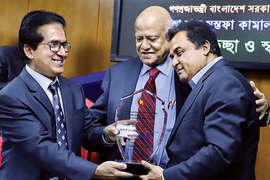 NBR Chairman Musharraf Hussain Bhuiyan presenting a crest to Finance Minister AHM Mustafa Kamal at the NBR office in the city on Thursday to welcome the incumbent minister and bid farewell to former Finance Minister AMA Muhith (Collected photo)