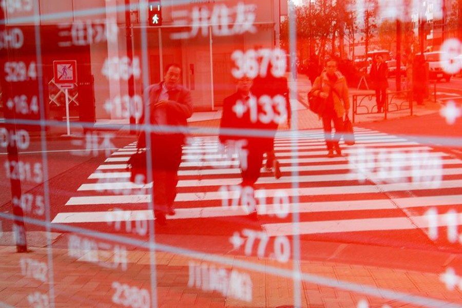 Pedestrians are reflected on an electronic board showing stock prices outside a brokerage in Tokyo, Japan, December 27, 2018. Reuters/Files