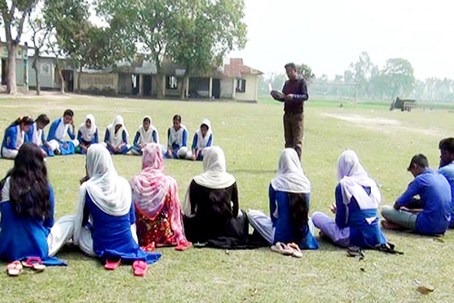 A teacher taking class under the open sky on the Mirzapur KC High School compound under Badalgachi upazila of Naogaon recently   	— FE Photo