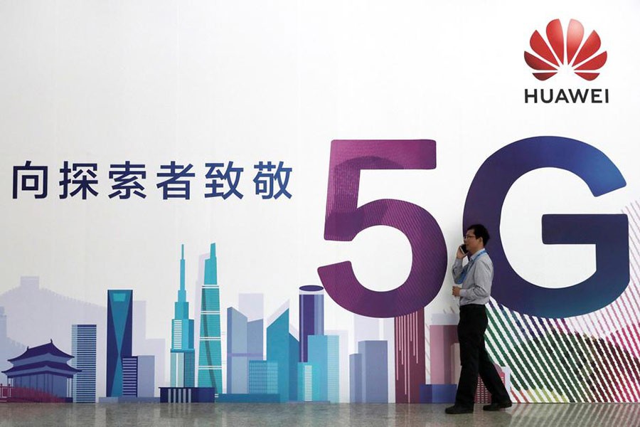 A man talks on his phone beside a Huawei billboard featuring 5G technology.  —Photo: Reuters