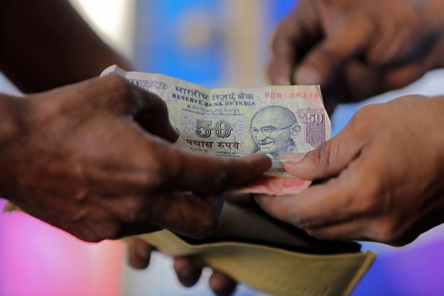 A customer hands a 50-Indian rupee note to an attendant at a fuel station in Ahmedabad, India, October 5, 2018. Reuters/Files