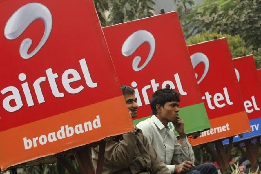 Men make phone calls as they sit on a railing with Bharti Airtel billboards installed on it, along a sidewalk in Kolkata February 1, 2013. REUTERS/Rupak De Chowdhuri/Files