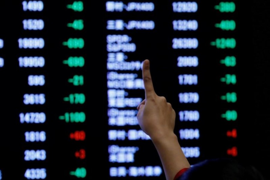 A woman points to an electronic board showing stock prices as she poses in front of the board after the New Year opening ceremony at the Tokyo Stock Exchange (TSE), held to wish for the success of Japan's stock market, in Tokyo, Japan, January 4, 2019. Reuters/File Photo