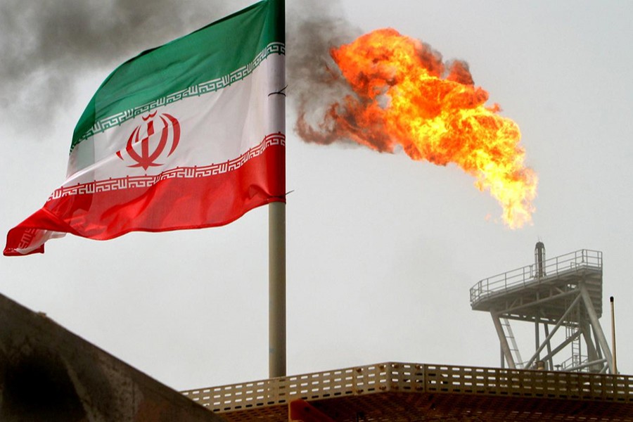 A gas flare on an oil production platform in the Soroush oil fields is seen alongside an Iranian flag in the Persian Gulf, Iran on July 25, 2005 — Reuters/Files