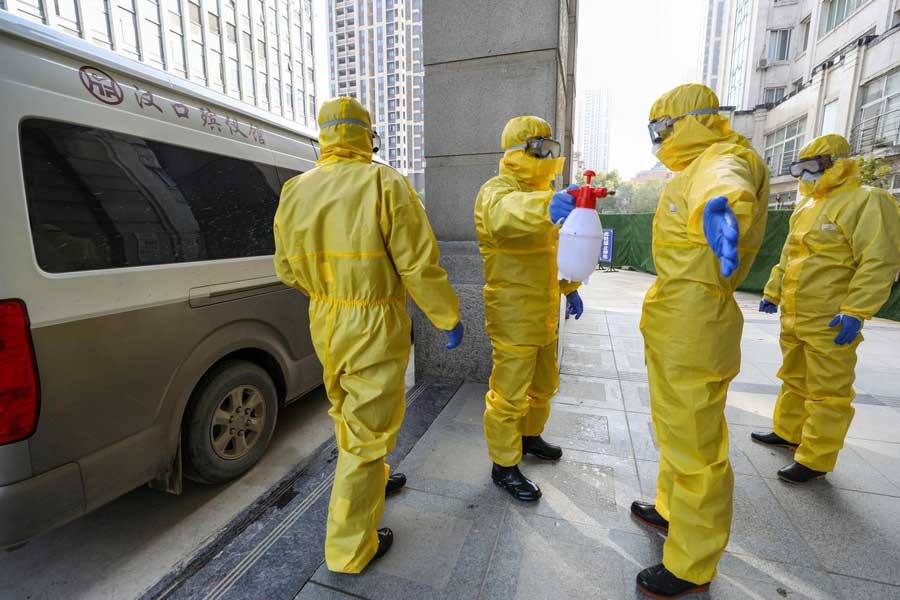 FILE PHOTO: Funeral parlour staff members in protective suits help a colleague with disinfection after they transferred a body at a hospital, following the outbreak of a new coronavirus in Wuhan, Hubei province, China January 30, 2020. China Daily via REUTERS/File Photo