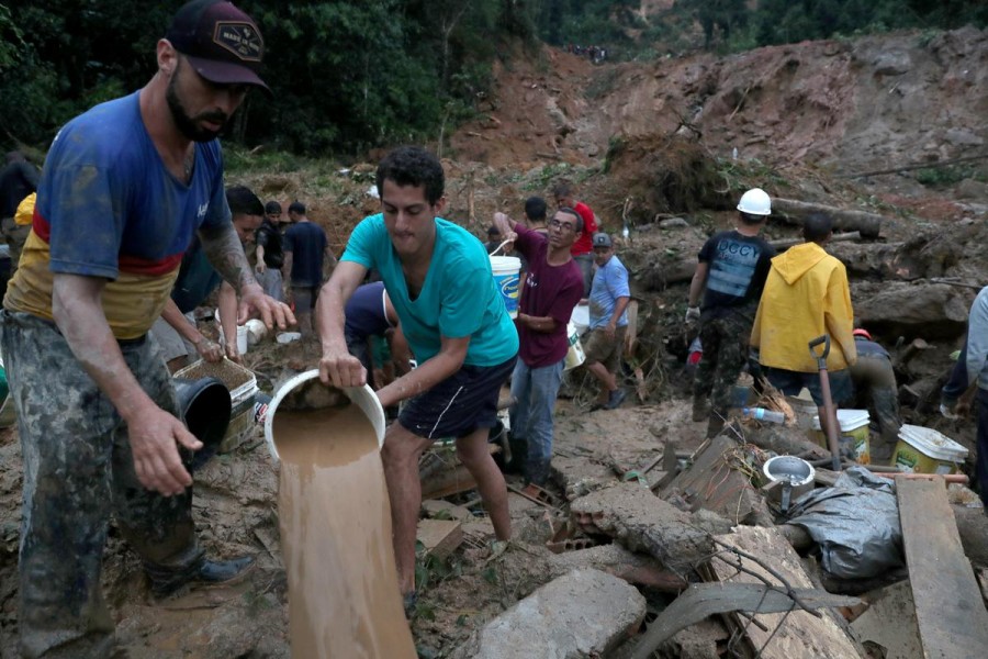 Residents carry buckets of mud and water, as firefighters (not pictured) dig for victims of a mudslide, where people remain missing at Barreira neighbourhood in Guaruja, Sao Paulo state, Brazil on March 3, 2020 — Reuters photo