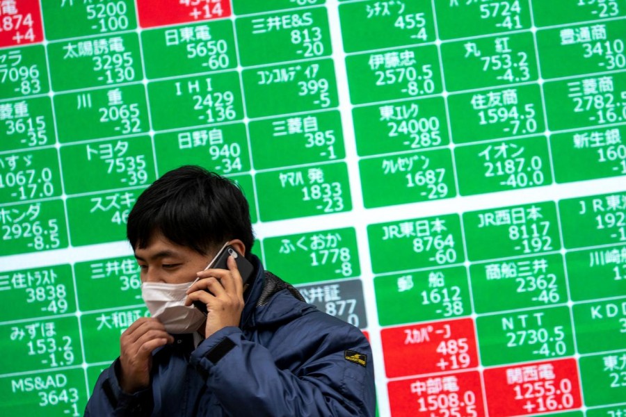 A man wearing a protective face mask, following an outbreak of the coronavirus, talks on his mobile phone in front of a screen showing the Nikkei index outside a brokerage in Tokyo, Japan, February 26, 2020 — Reuters