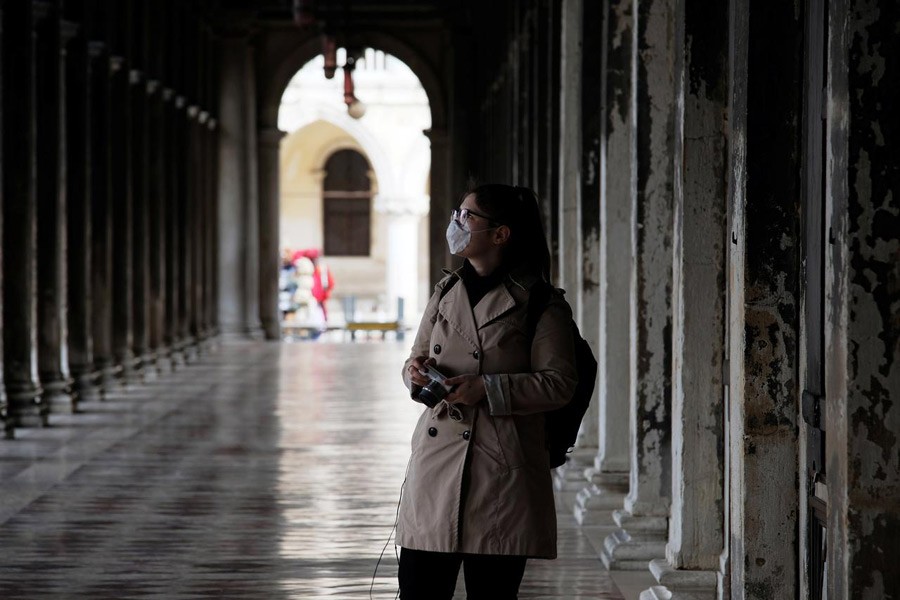 A woman wearing a protective face mask walks through St. Mark's Square after the Italian government imposed a virtual lockdown on the north of Italy including Venice to try to contain a coronavirus outbreak, in Venice, Italy, March 09, 2020 — Reuters