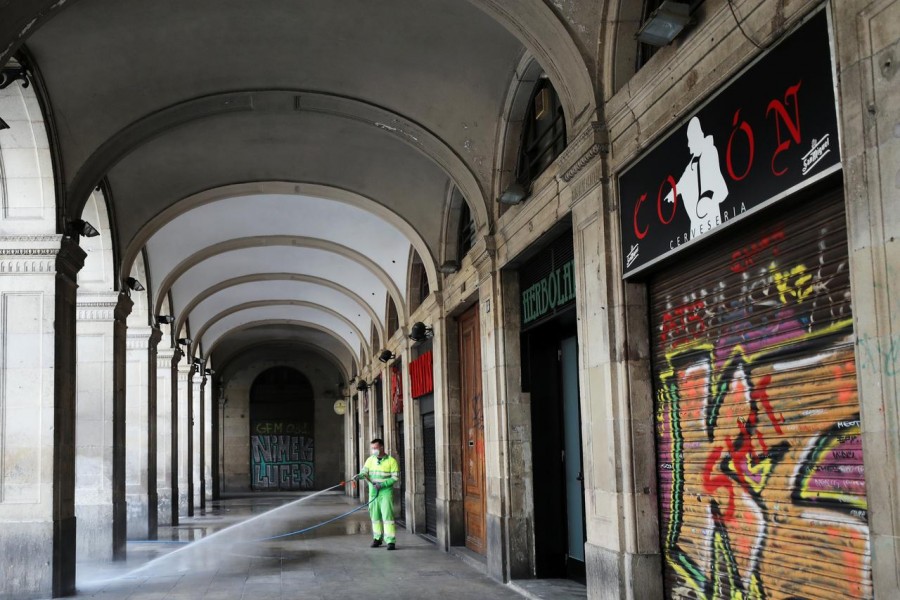 A worker wears a protective face mask as he washes the empty Plaza Reial (Reial Square), amidst concerns over coronavirus outbreak, in Barcelona, Spain March 14, 2020. REUTERS/Nacho Doce