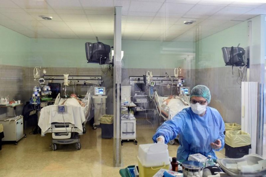 A medical worker wearing a protective mask and suit treats patients suffering from coronavirus disease (COVID-19) in an intensive care unit at the Oglio Po hospital in Cremona, Italy, March 19, 2020. — Reuters