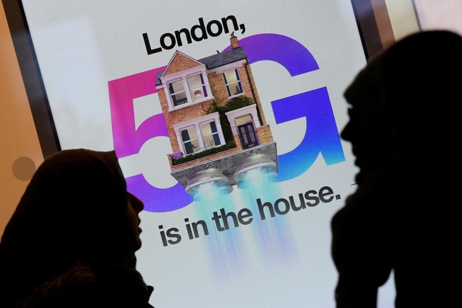 Pedestrians walk past an advertisement promoting the 5G data network at a mobile phone store in London, Britain, January 28, 2020. REUTERS/Toby Melville