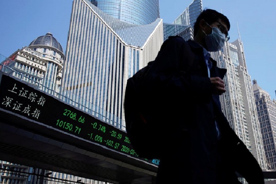 A pedestrian wearing a face mask walks near an overpass with an electronic board showing stock information, following an outbreak of the coronavirus disease (COVID-19), at Lujiazui financial district in Shanghai, China, March 17, 2020. — Reuters/Files