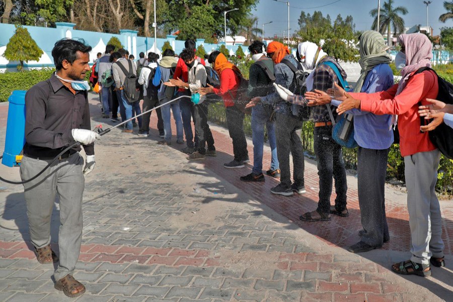 A municipal worker sprays disinfectant on migrant workers before they board a bus to return to their villages, during a 21-day nationwide lockdown to slow the spread of coronavirus disease (COVID-19), in Lucknow, India on March 30, 2020 — Reuters/Files