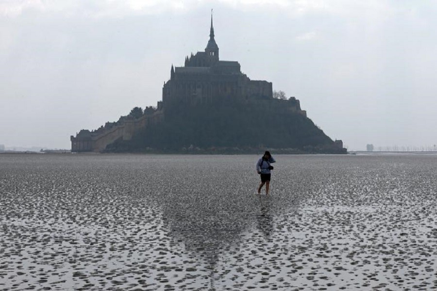 Representational image: A woman walks on the sand at low tide around the Mont Saint-Michel 11th century abbey off France's Normandy coast March 21, 2015. — Reuters/Files