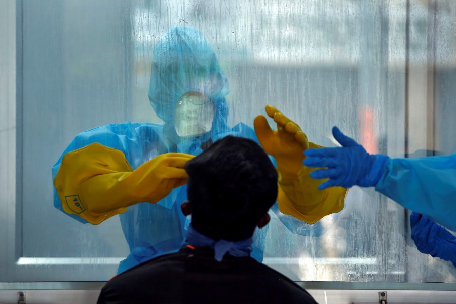 A doctor in a protective chamber takes a swab from a man to test for coronavirus disease (COVID-19) at a Walk-In Sample Kiosk (WISK) in a government-run hospital in Chennai — Reuters/Files