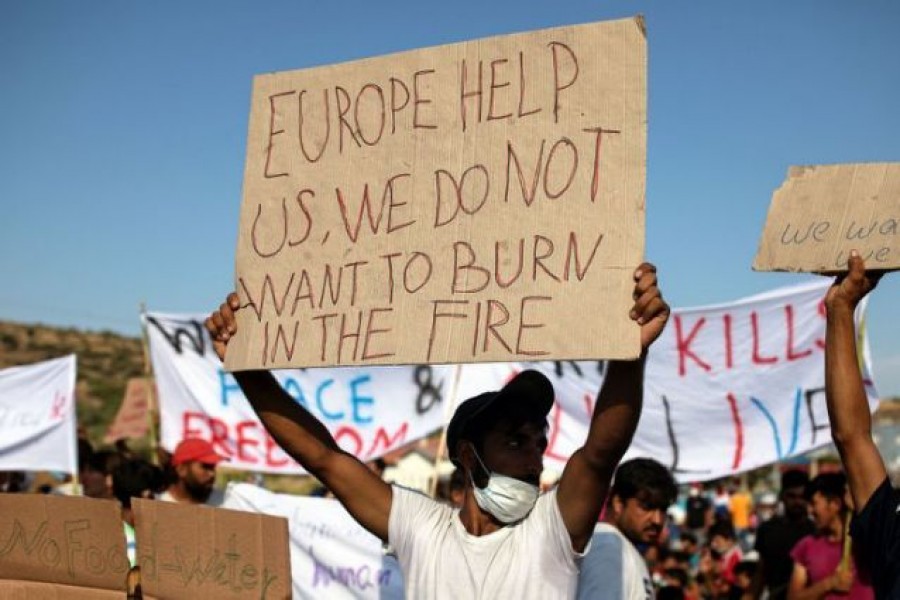 A man holds a placards as refugees and migrants from the destroyed Moria camp protest after the news about the creation of a new temporary camp, on the island of Lesbos, Greece September 12, 2020. REUTERS/Alkis Konstantinidis