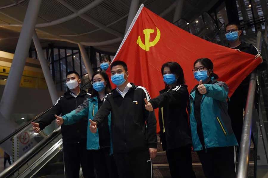 Medical workers from outside Wuhan posing for pictures with a Chinese Communist Party flag at the Wuhan Railway Station before leaving the city in March this year –Reuters file photo