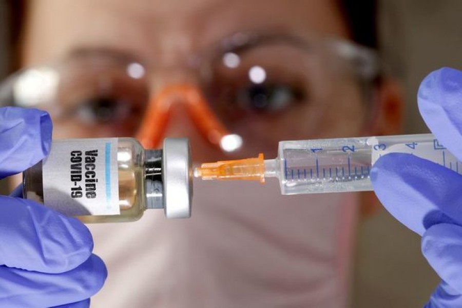 A woman holds a small bottle labelled with a "Vaccine COVID-19" sticker and a medical syringe in this illustration taken April 10, 2020 -- Reuters/Files