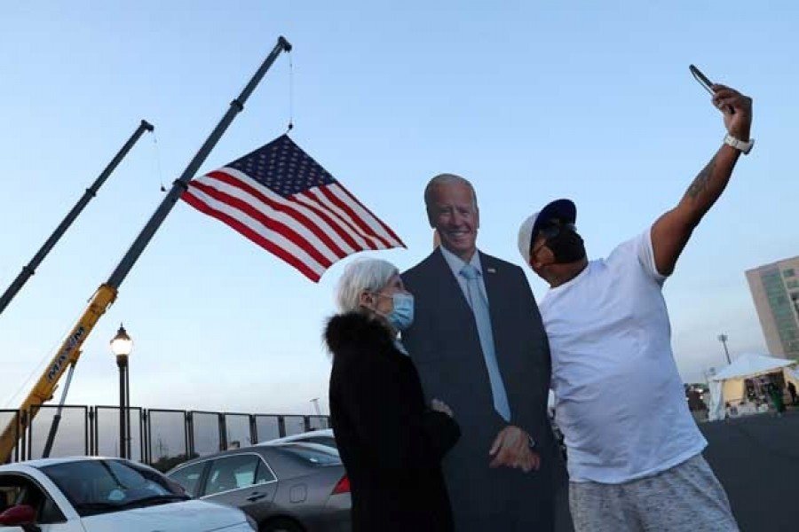 Supporters including Jo Lawlor of Pennsylvania (L) pose for photographs with a cutout of former Vice President Joe Biden near the site where Biden and Senator Kamala Harris hope to celebrate their victory in the US presidential race in Wilmington, Delaware, Nov 5, 2020. REUTERS