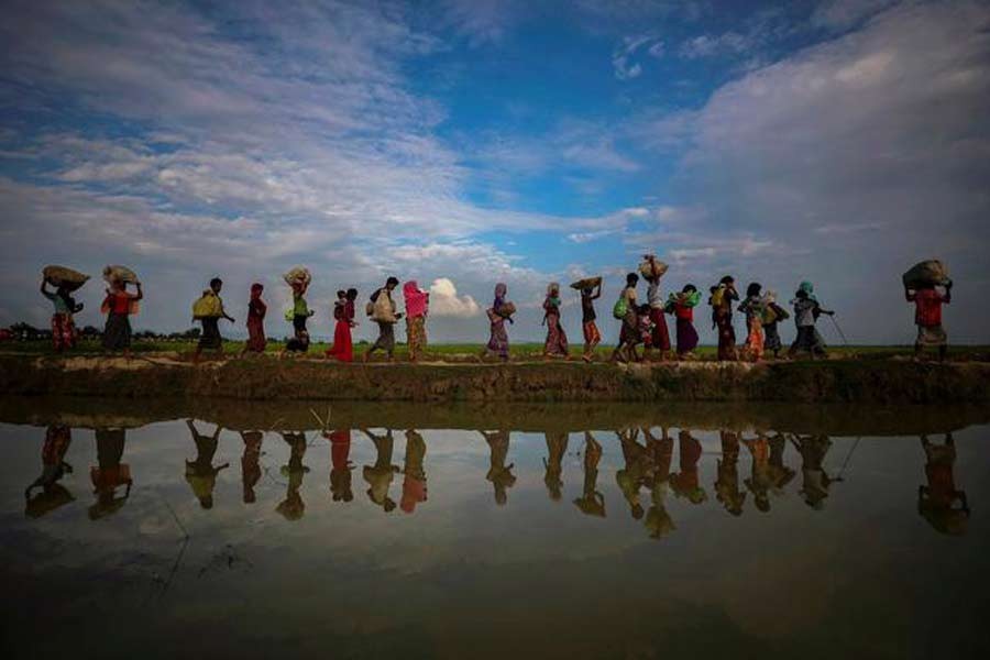 Rohingya refugees are reflected in rainwater along an embankment next to paddy fields after fleeing from Myanmar into Palang Khali near Cox's Bazar in 2017 –Reuters file photo