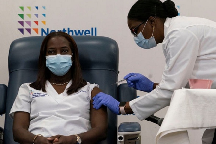 Sandra Lindsay, a nurse at Long Island Jewish Medical Center, is inoculated with the coronavirus disease (COVID-19) vaccine by Dr Michelle Chester from Northwell Health at Long Island Jewish Medical Center in New Hyde Park, New York, US, December 14, 2020. REUTERS