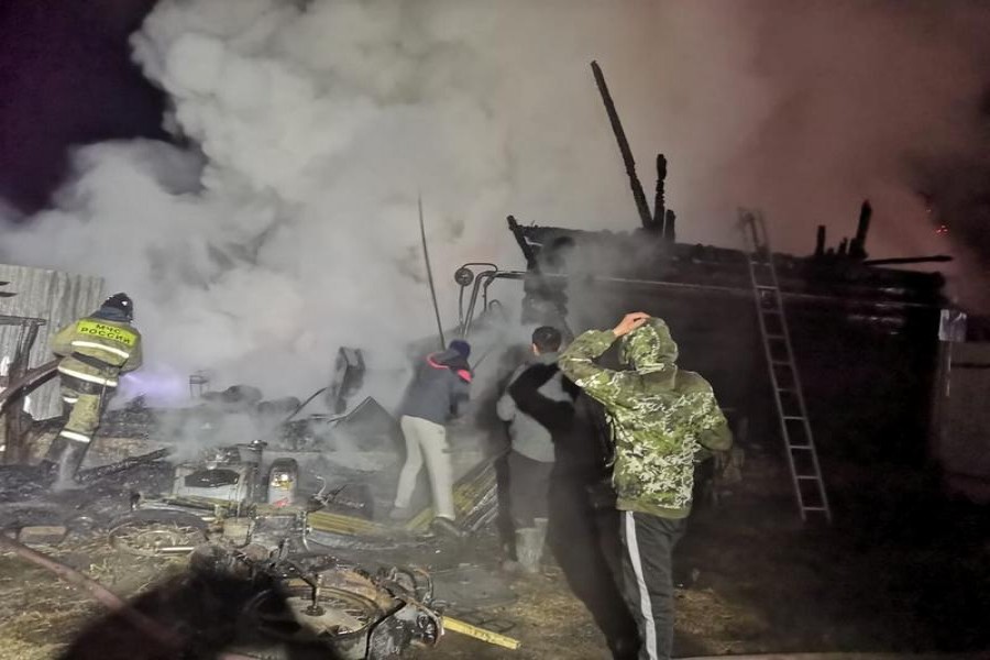 A firefighter and local residents are seen on a site of fire in a retirement home at the village of Ishbuldino, Russia December 15, 2020. Russian Emergencies Ministry/Handout via REUTERS