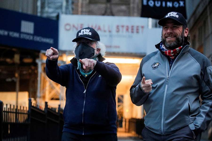 Trader Peter Tuchman and specialist trader Michael Pistillo greeting friends as they exit the New York Stock Exchange, (NYSE) wearing DOW 30,000 hats, in New York last month –Reuters file photo