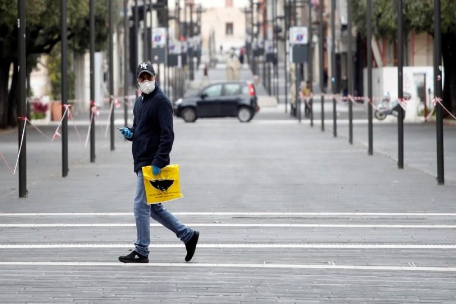 A man wearing a protective face mask walks on a street in Bari as the spread of the coronavirus disease (COVID-19) continues, in Bari, Italy, March 27, 2020. REUTERS/Alessandro Garofalo