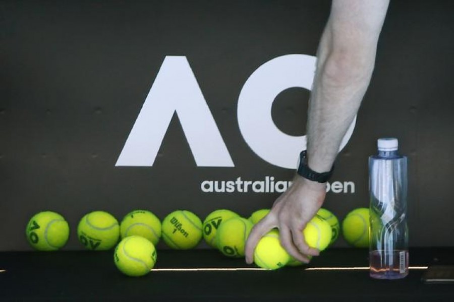 A person picks up tennis balls in front of the Australian Open logo — Reuters/Files