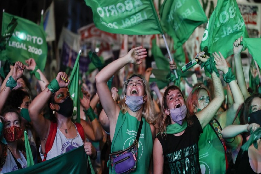 Abortion-rights activists watch live video streaming of lawmakers in session, outside Congress in Buenos Aires, Argentina, Wednesday, Dec. 30, 2020. Congress approved a bill that legalize abortion in Argentina. (AP Photo/Natacha Pisarenko)