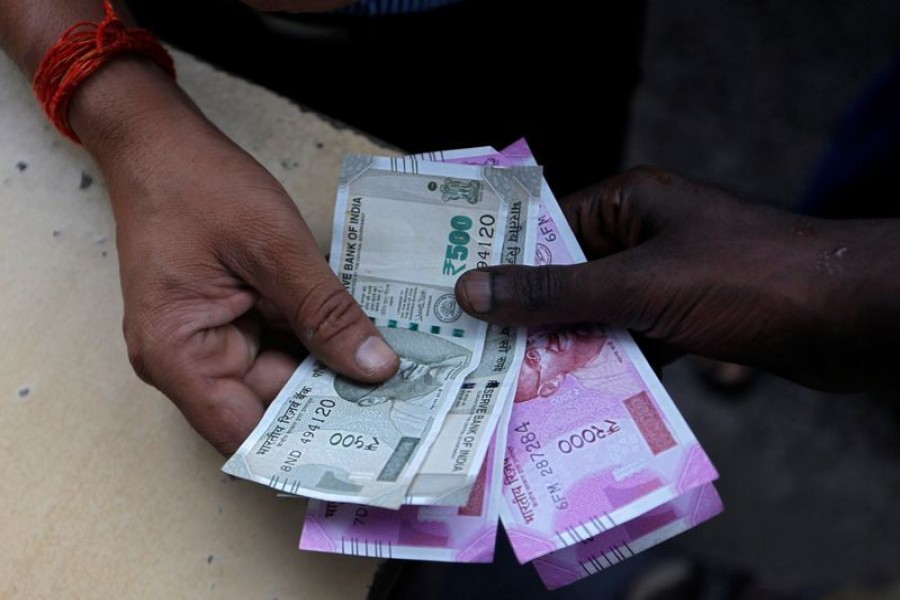 A customer hands Indian currency notes to an attendant at a fuel station in Mumbai