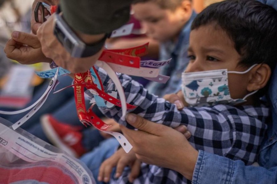 FILE PHOTO: A US Border Patrol Agent removes a wristband worn by Santiago, a four year old asylum seeking migrant boy from Honduras, after he crossed the Rio Grande river into United States from Mexico with his mother in Penitas, Texas, US, March 9, 2021. REUTERS/Adrees Latif