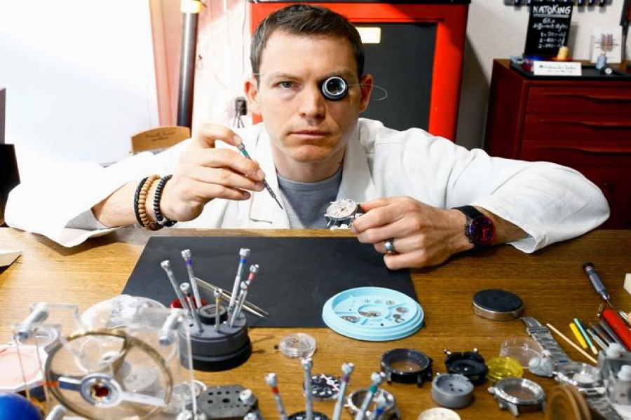 Former Swiss soccer player Stephan Lichtsteiner wears a magnifier as he holds the movement of a watch during his internship at the production facility of Swiss watch manufacturer Maurice de Mauriac in Zurich, Switzerland March 12, 2021. Picture taken March 12, 2021. REUTERS/Arnd Wiegmann