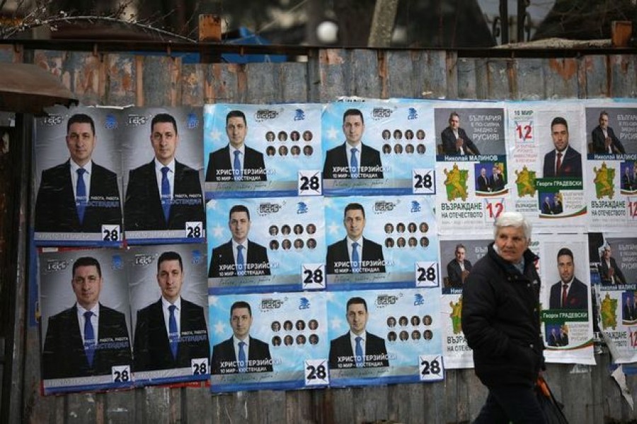 FILE PHOTO: A woman walks past election posters of the ruling centre-right GERB party in the town of Dupnitsa, Bulgaria, April 2, 2021. REUTERS/Stoyan Nenov