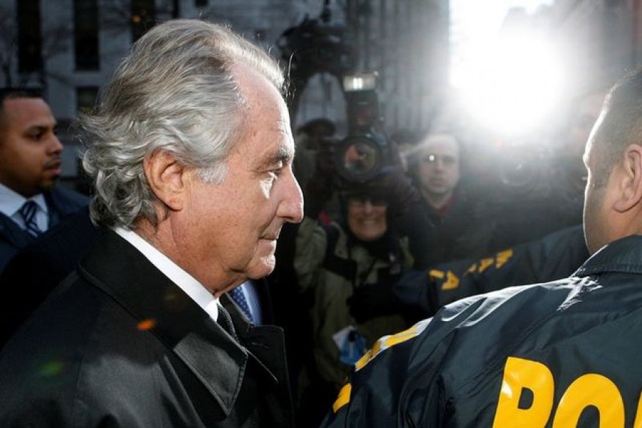 FILE PHOTO: Disgraced financier Bernard Madoff is escorted by police and photographed by the media as he departs U.S. Federal Court after a hearing in New York, January 5, 2009. REUTERS/Lucas Jackson/File Photo