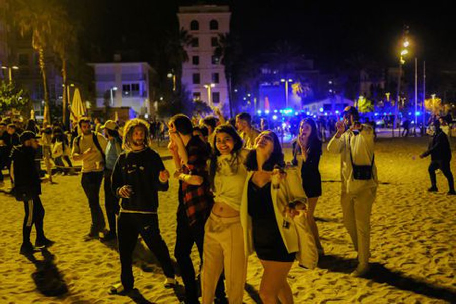 People gather in front of police officers patrolling Barceloneta beach, as the state of emergency decreed by the Spanish Government to prevent the spread of the coronavirus (COVID-19) was lifted a week ago in Barcelona, Spain, May 15, 2021. Picture taken May 15, 2021. REUTERS/Nacho Doce