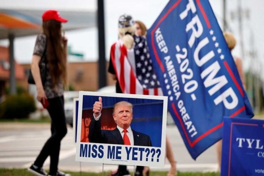 Supporters of former US President Donald Trump gather on a street corner near a sign saying "Miss Me Yet???" outside the North Carolina GOP convention before Trump was expected to speak at the gathering in Greenville, North Carolina, US June 5, 2021. REUTERS